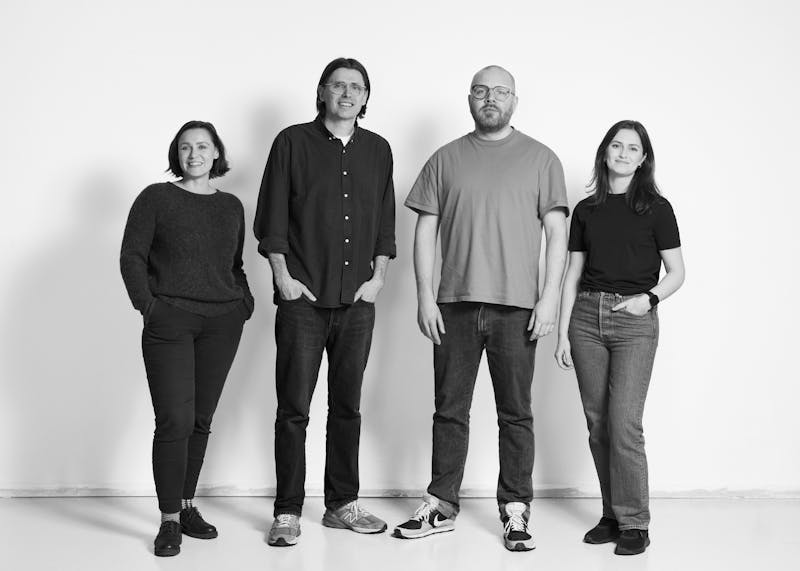 Full length black-and-white photo of the Brak staff. Four people, two women and two men are facing the camera.